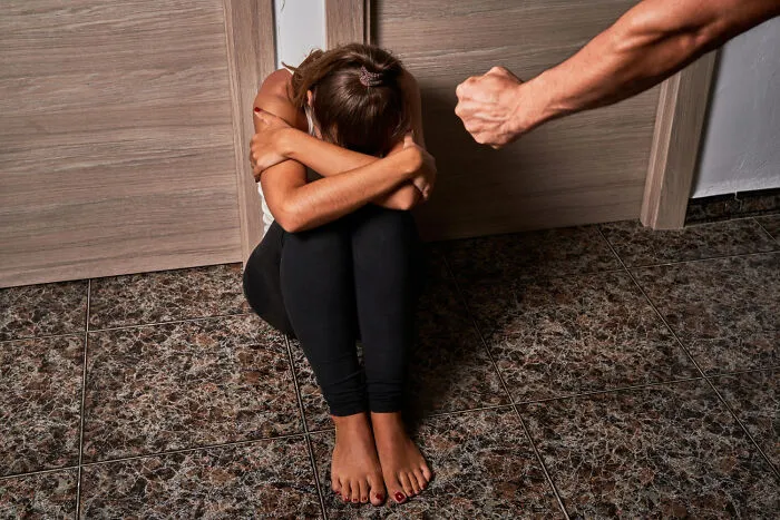 Terrified girl on floor with a fist nearby illustrating being disowned by their families