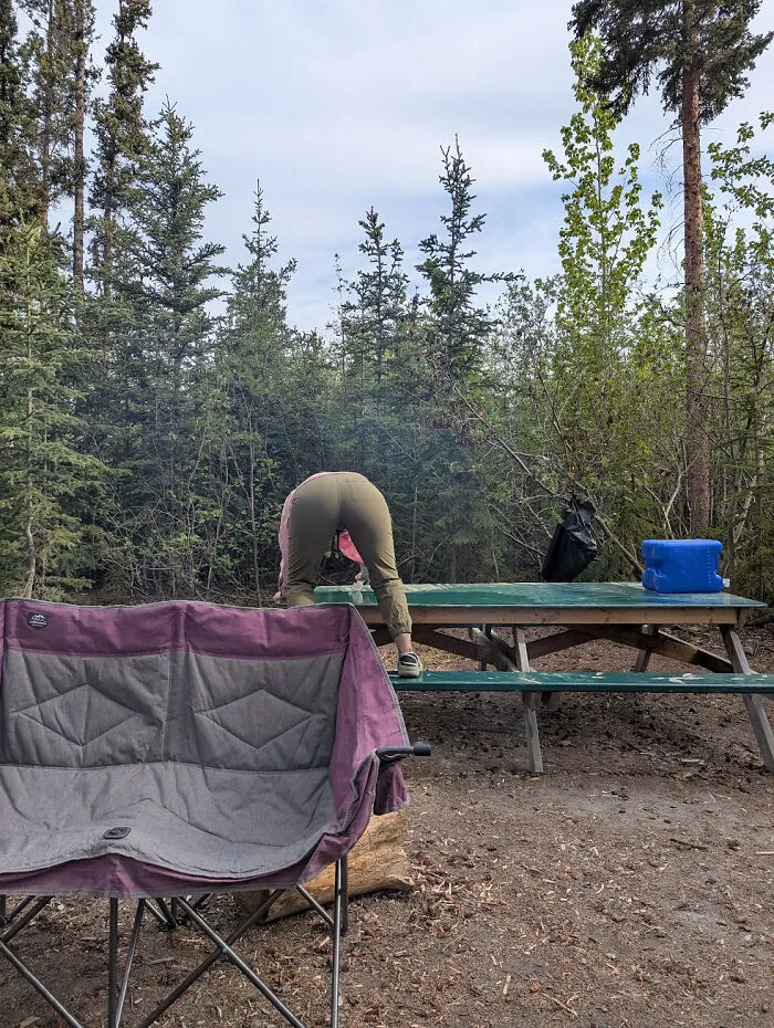 Husbands' funniest quirks: a wife leaning over a picnic table while camping.