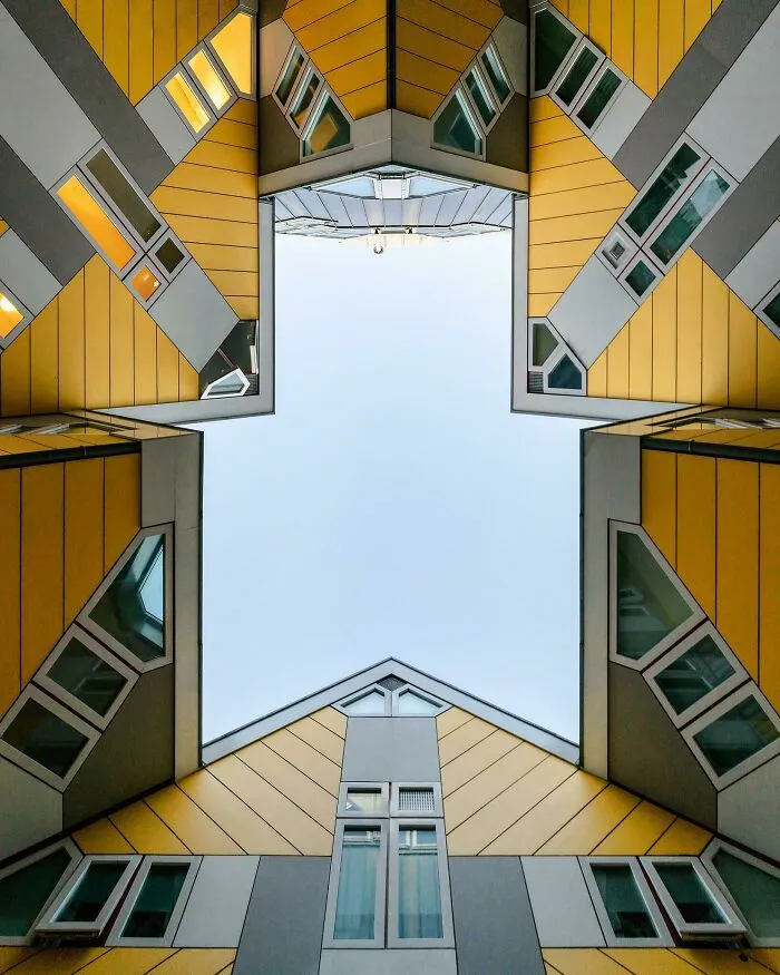 A low angle view of yellow cube houses with a bizarre shape against a blue sky.