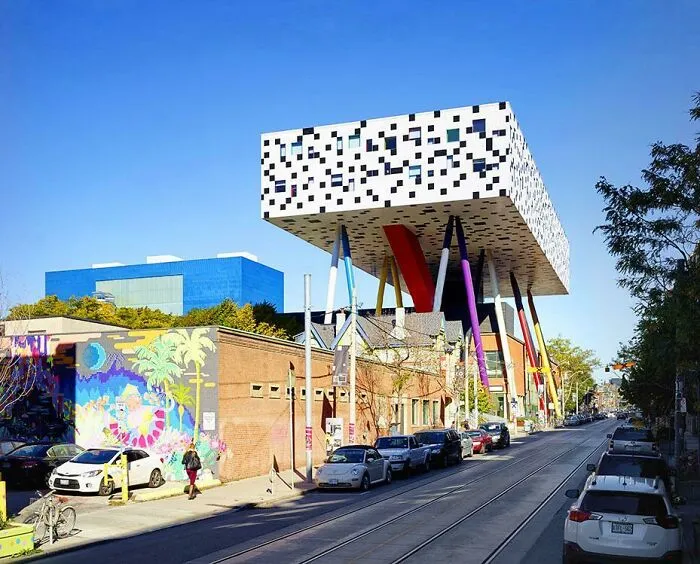 A modern building with bizarre shapes of black and white pixel patterns standing on colorful stilts.