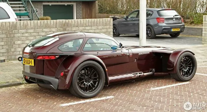 Rear view of a dark red Donkervoort sports car, one of many wonderful vehicles, parked outdoors.