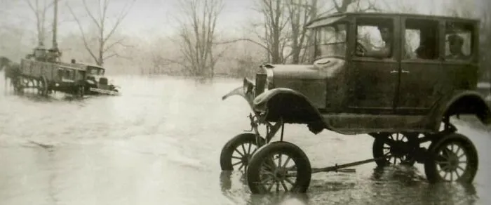 Vintage car modified with high lifted suspension driving through floodwaters, representing weird and wonderful vehicles.