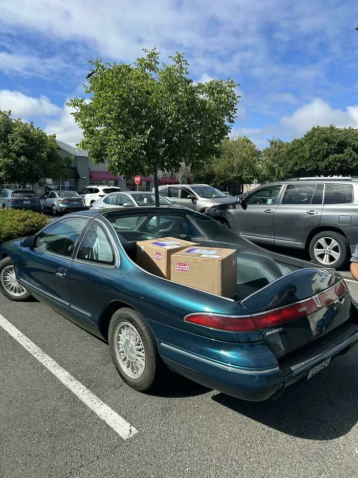 A custom dark blue luxury coupe modified into a pickup truck carrying boxes, one of wonderful vehicles.