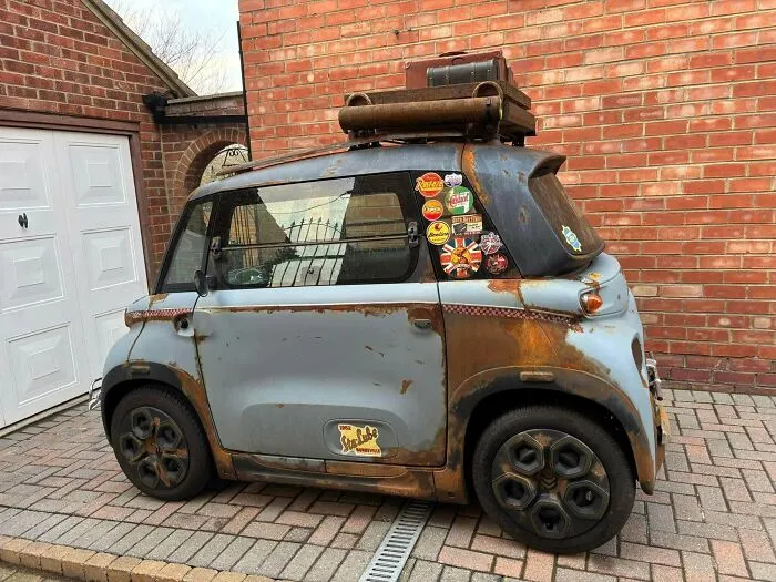 Rusted retro microcar with roof luggage rack parked outside, one of many wonderful vehicles.