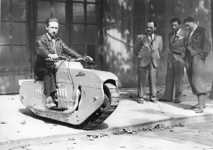 Vintage black and white photo of a man riding a custom tracked single-tread motorcycle, showing wonderful vehicles.