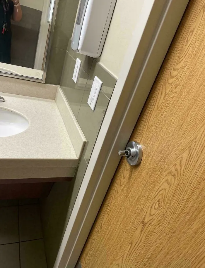 A public bathroom door handle installed too close to the counter wall indicating things went wrong