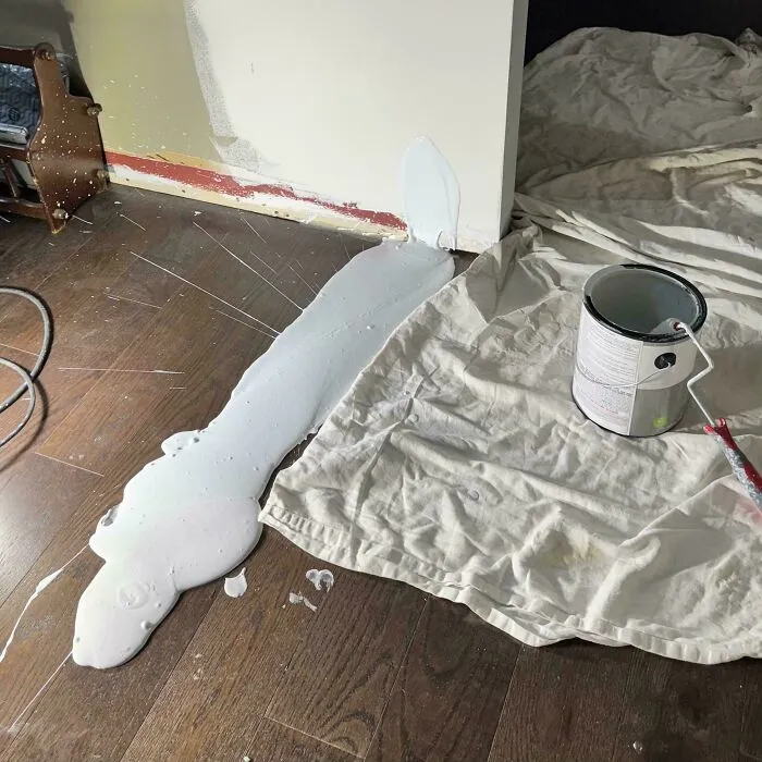 White paint spilled on a wooden floor showing things went wrong during a DIY home renovation project