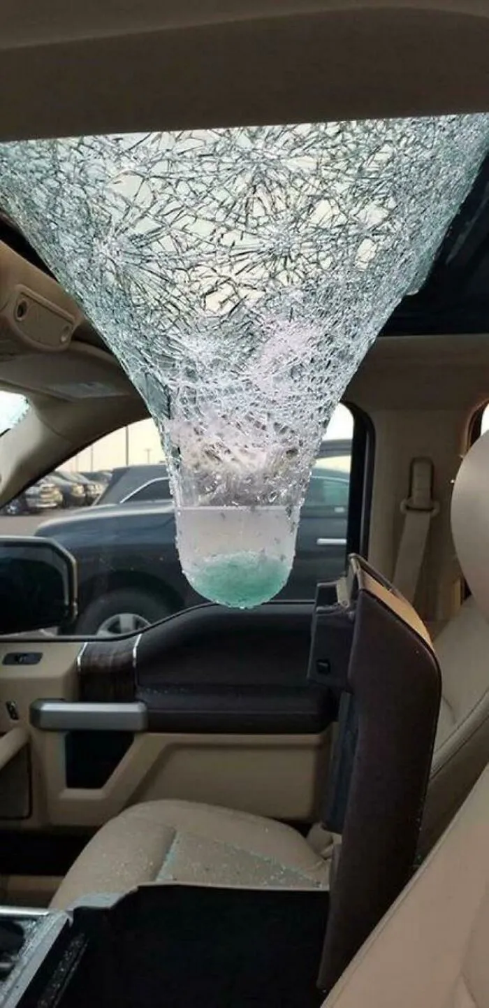A shattered car sunroof holding water like a funnel inside the cabin.