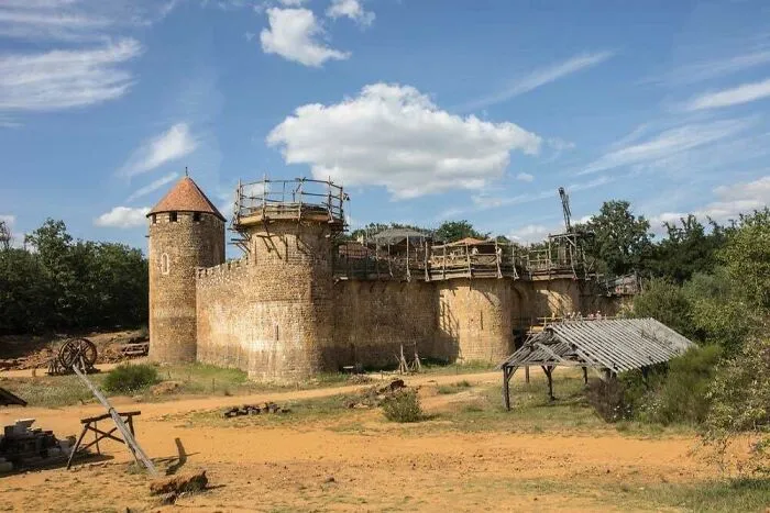 A medieval-style castle undergoing construction in a dusty field, showing how buildings turn heads with bizarre shapes
