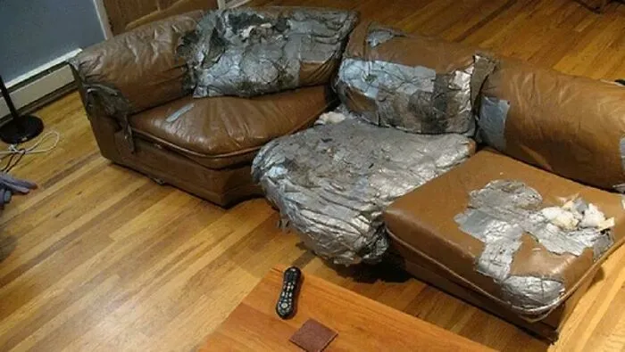 A terrible DIY project of a brown leather sectional sofa heavily patched and repaired with grey duct tape