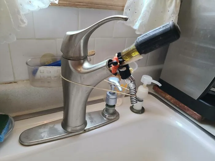 A kitchen faucet held together with a screwdriver and rubber bands, showing DIY projects.