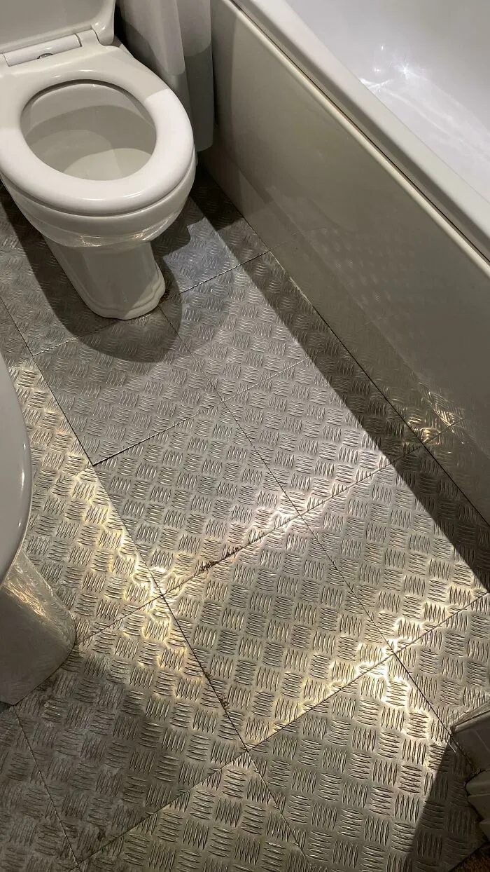 DIY projects bathroom flooring with textured silver metal diamond plate tiles installed next to a toilet.