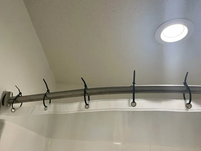 Simple DIY projects using black zip ties as hangers on a shower curtain rod holding a clear liner.