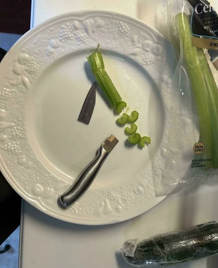 A small paring knife snapped in half on a white plate while cutting a celery stalk.