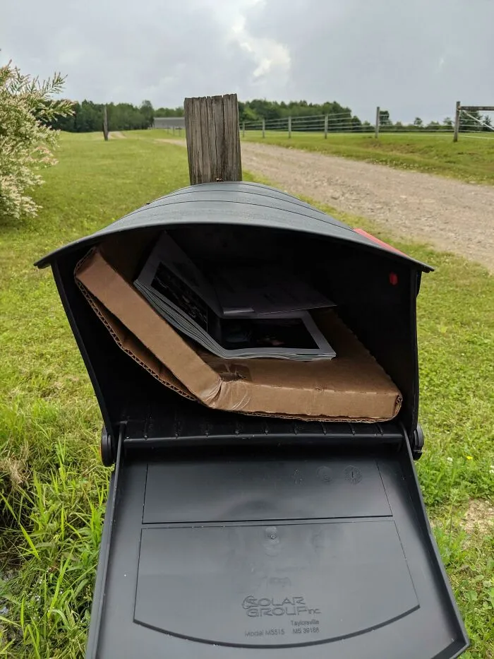 A bent cardboard package stuffed into a rural mailbox. Things Went Wrong Pics