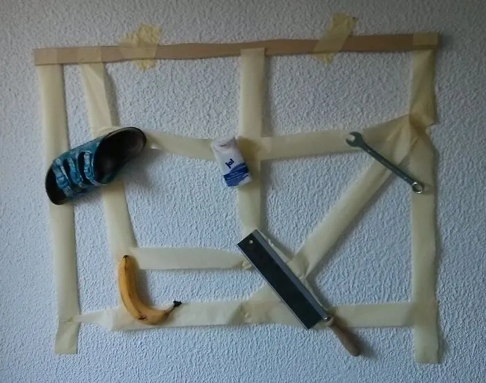 A humorous DIY project featuring a banana, shoe, and tools taped to a wall