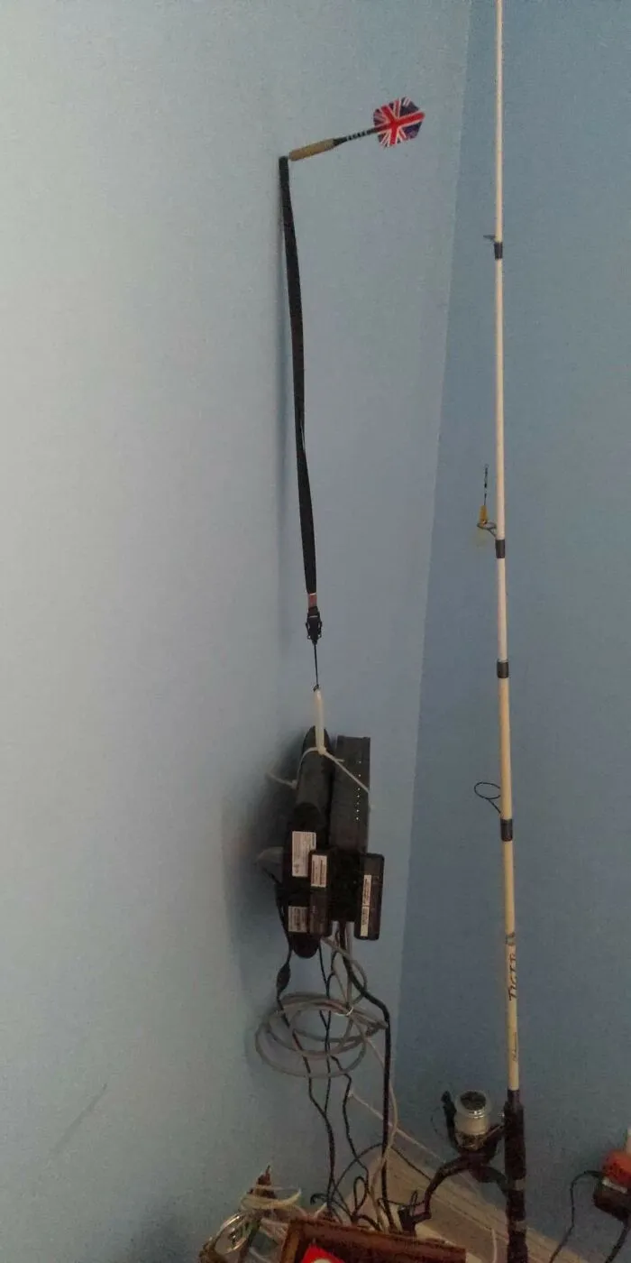 Funny DIY Projects setup using a wall dart to hang internet router wires on a blue wall.