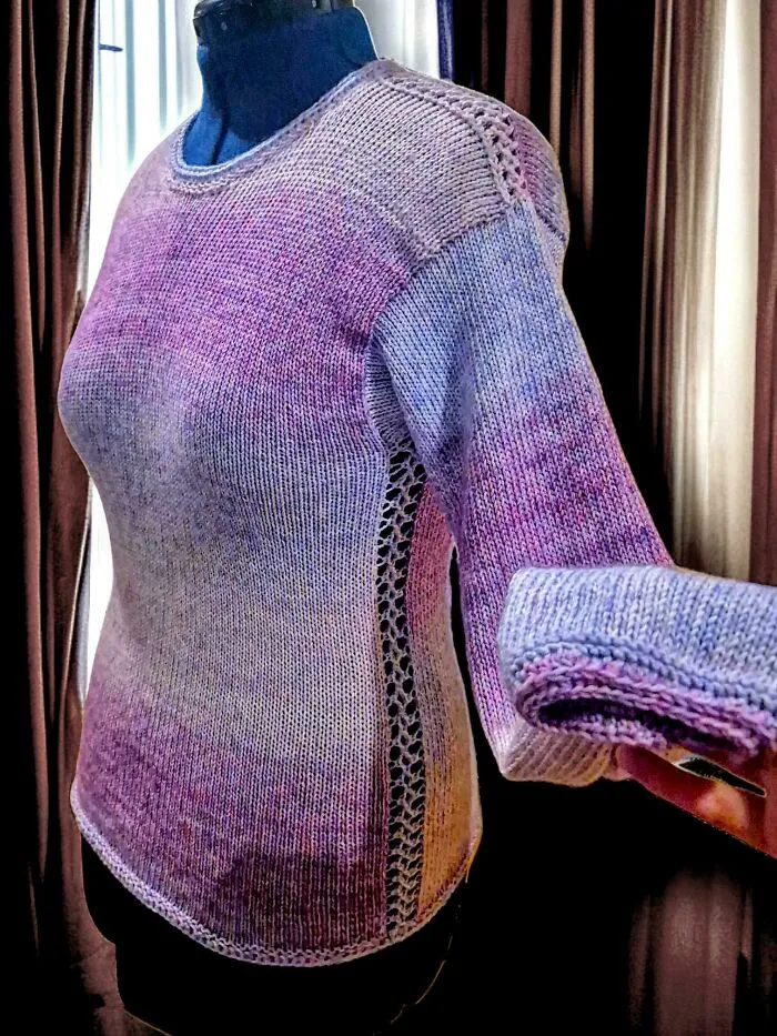 A hand knitting purple and blue ombre sweater on a mannequin display