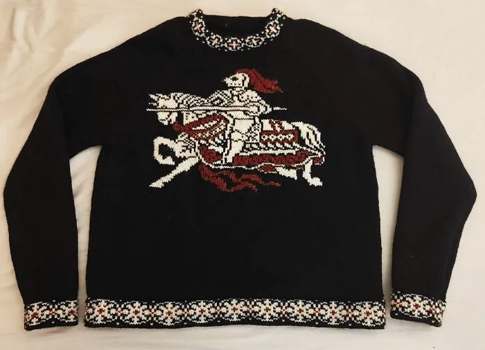 A black knitting sweater featuring a white and red knight on a horse design