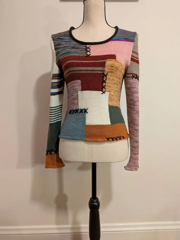 A multi-colored patchwork sweater on a mannequin, showcasing skills of knitting amateurs
