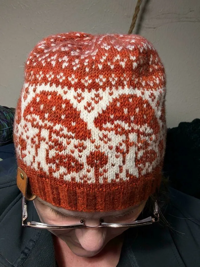 A cozy knitting project showcasing a hand-knit orange and white mushroom-patterned beanie