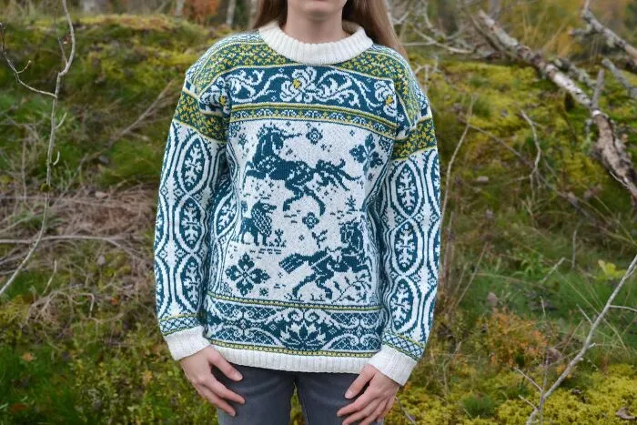 A detailed knitting project showing a person wearing an intricate blue and white sweater with unicorn designs