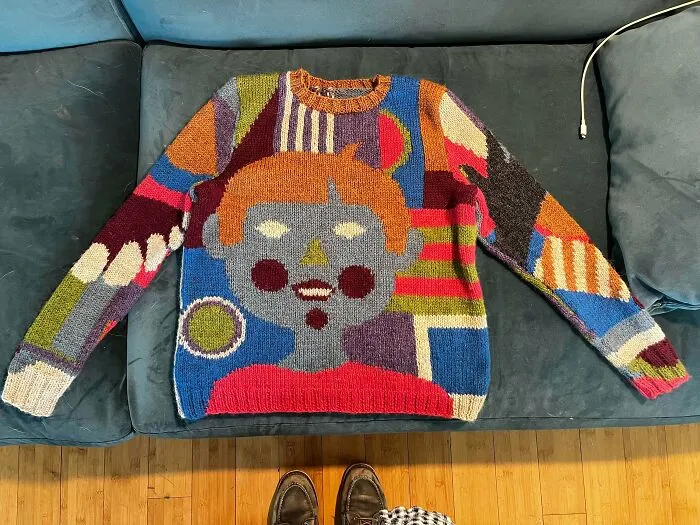 An artistic and colorful hand-knitted sweater with a face design by knitting amateurs and pros