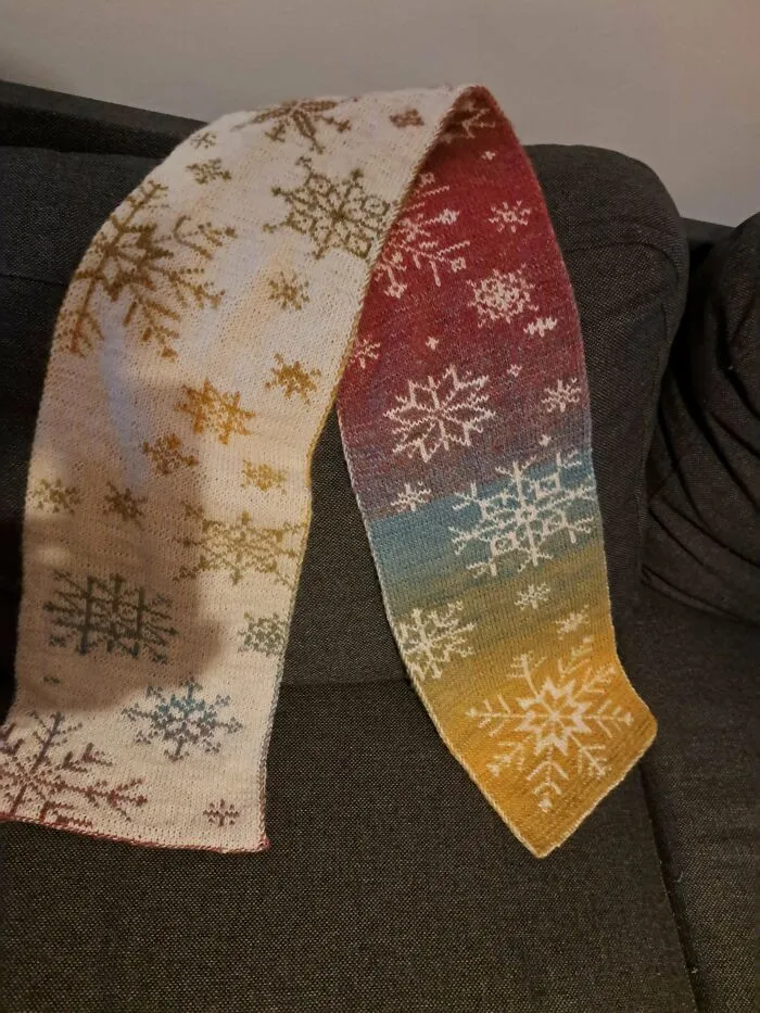 A colourful knitted scarf featuring snowflake patterns, showing knitting hobby creativity.