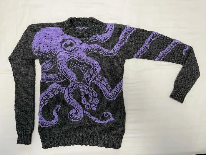 A grey knitted sweater with a purple octopus pattern, demonstrating advanced knitting hobby craft.