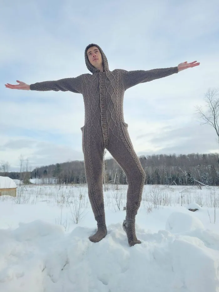 A man wearing a full-body knitted jumpsuit in the snow, showcasing creative knitting ideas