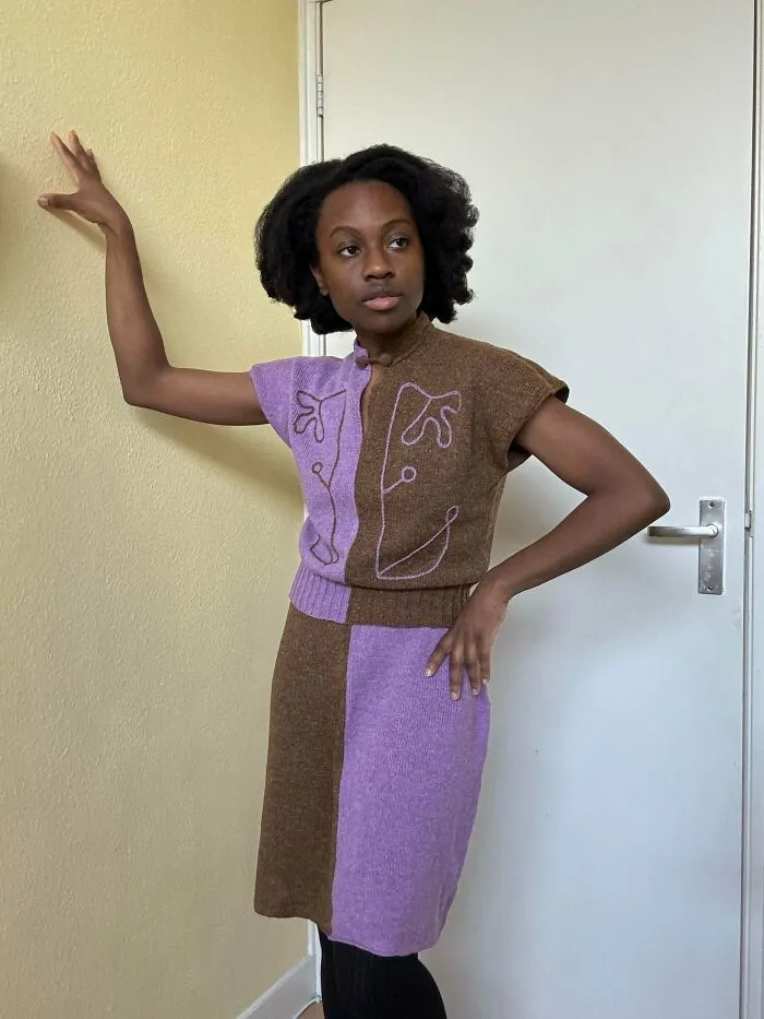 A woman posing in a half-purple and half-brown knitted dress with embroidered details, showing knitting ideas