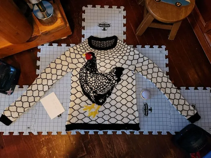 A white and black knitted sweater with a chicken design, demonstrating unique knitting patterns