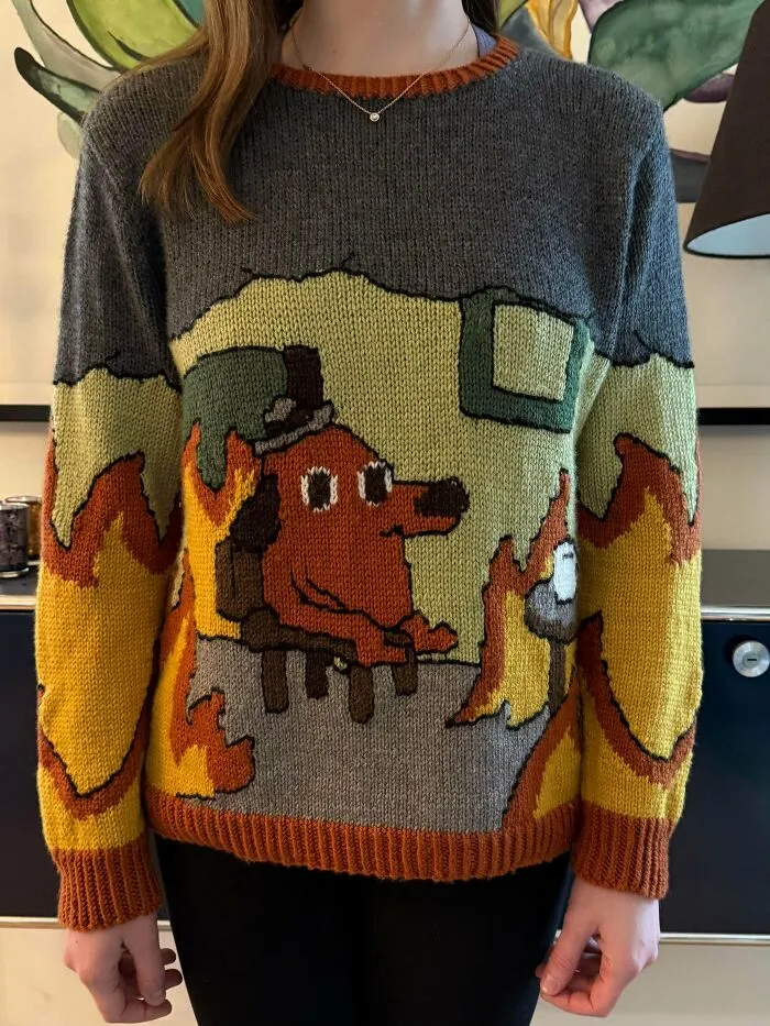 A person wearing a custom knit sweater featuring the famous This is fine dog meme.
