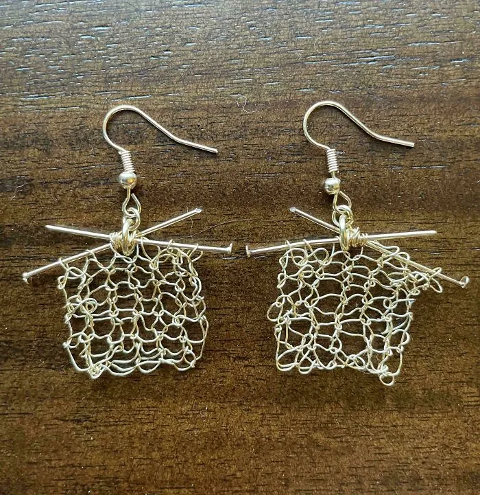 A pair of earrings creatively designed as knitting in progress on tiny needles.