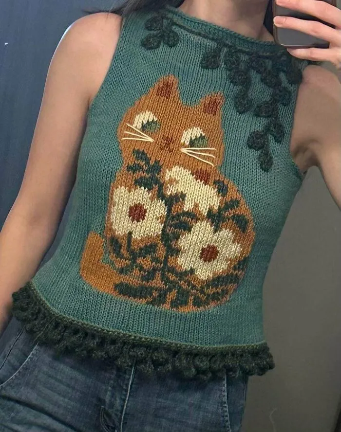 Close-up of a teal sleeveless top with a cute knitting cat and flower pattern.