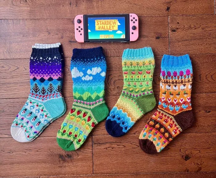 Four pairs of colorful knitting socks themed after Stardew Valley seasons next to a Nintendo Switch.
