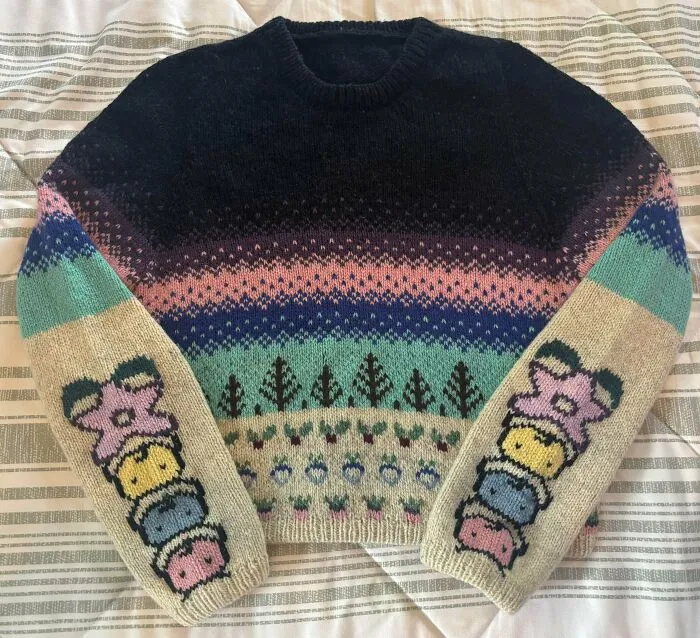 Colorful patterned sweater with cute figures on the sleeves, showcasing a creative knitting hobby project.