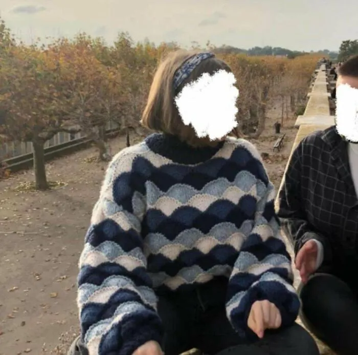 A person wearing a stylish blue and white wave-patterned sweater, showing off a unique knitting hobby design.