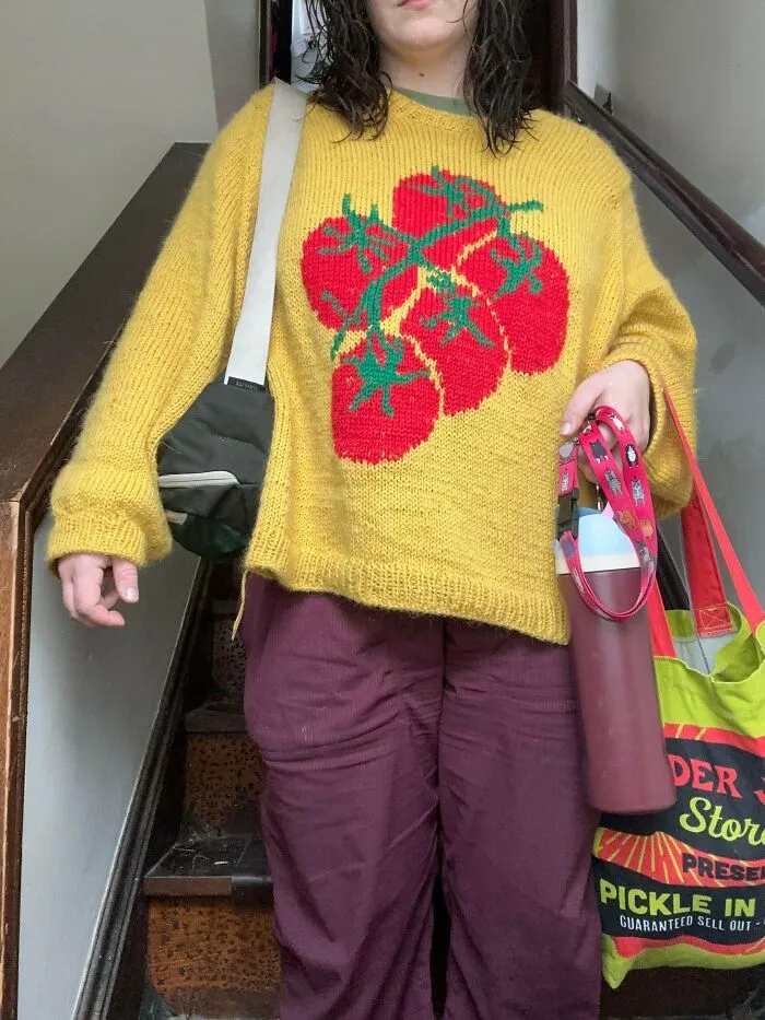 A hand-knitted yellow sweater with red tomatoes, showing a creative project by knitting amateurs and pros.