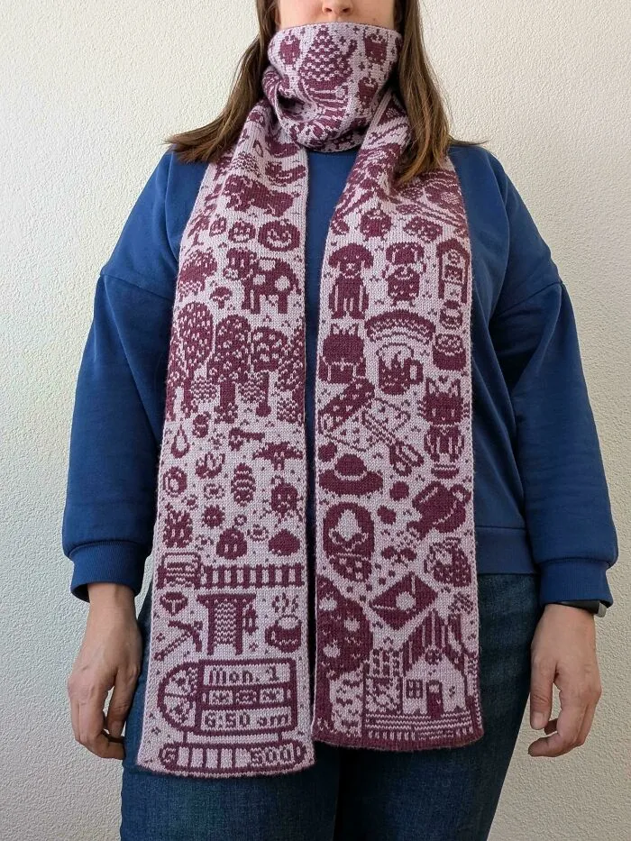 A woman wearing a purple and white knitted scarf, showing the work of skilled knitting amateurs and pros