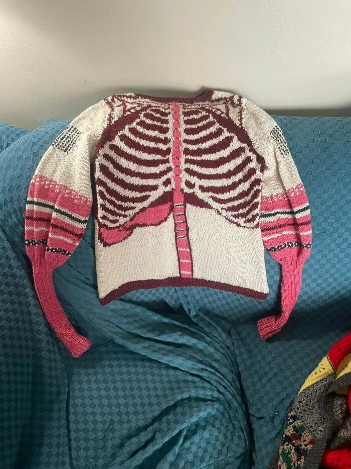 A white and pink sweater with a knitted rib cage design, showcasing creative knitting amateurs and pros designs