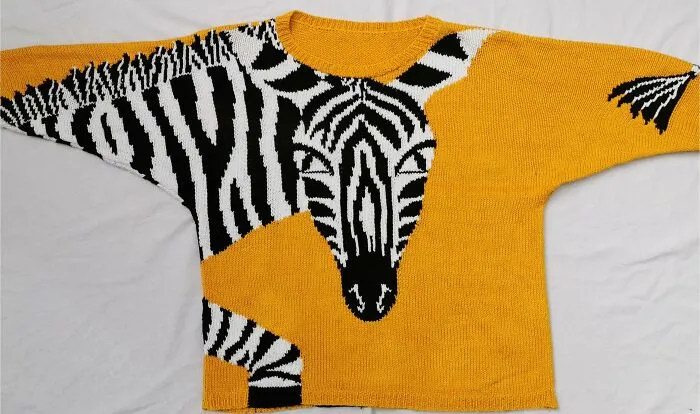 A yellow knitted sweater featuring a black and white zebra design, showing the art of knitting amateurs and pros