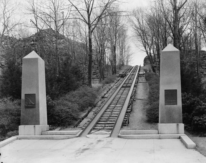 Historical treasures view of an old inclined railway track flanked by two stone obelisks in a forest.