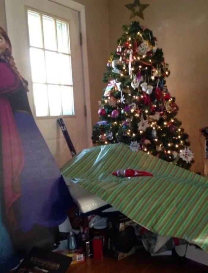 An elf on the shelf on a collapsed gift wrap showing things went wrong.