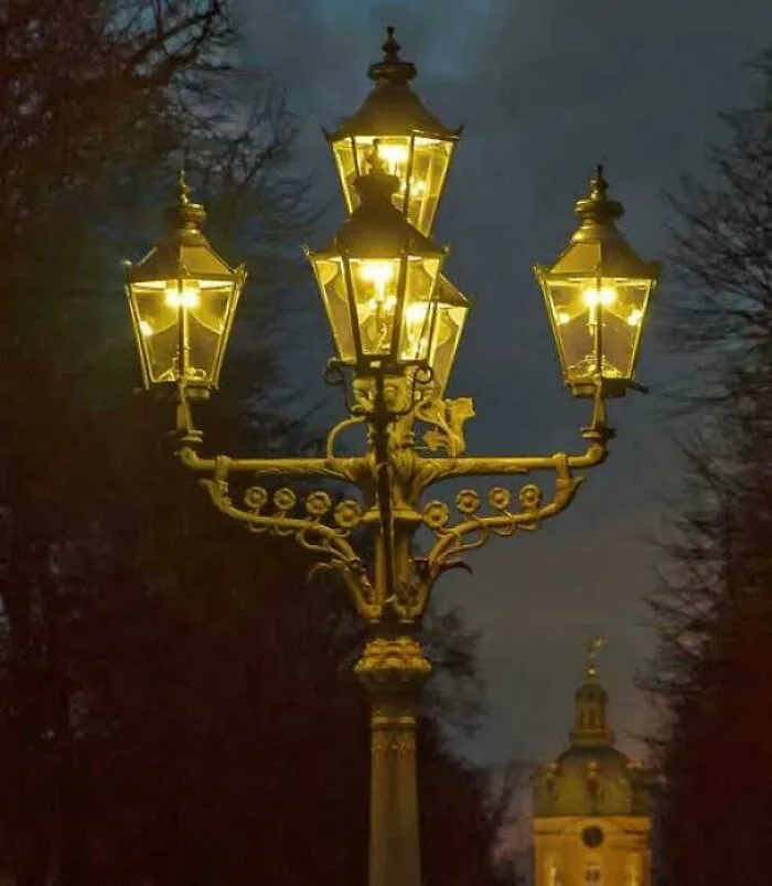 Ornate antique gas street lamp illuminated at night, an example of a historical treasure.