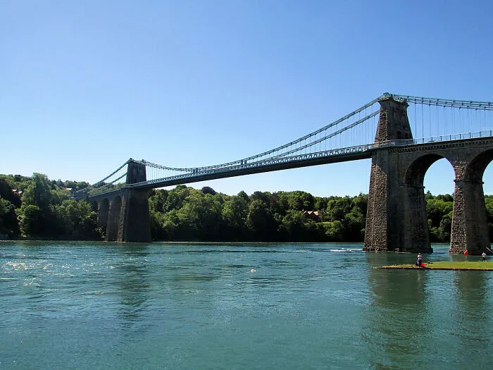 The Menai Suspension Bridge over water, showcasing historical treasures from two centuries ago.