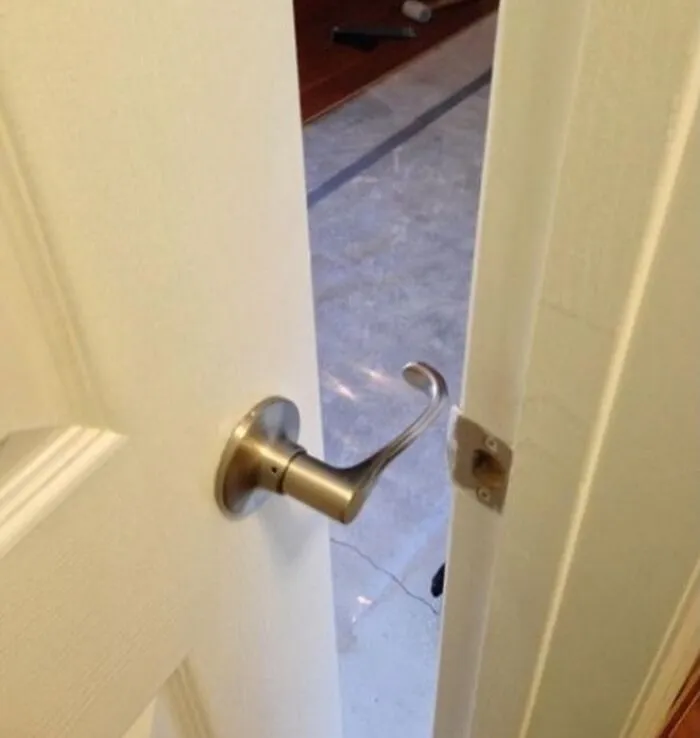 A failed DIY project showing a door handle installed on the wrong side of the door next to the latch