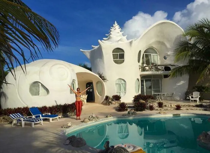 A unique seashell-themed house showcasing bizarre shapes in residential architecture by a pool.