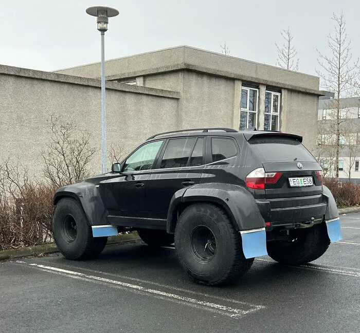 A modified black SUV with oversized off-road tires parked outside, showcasing wonderful vehicles.
