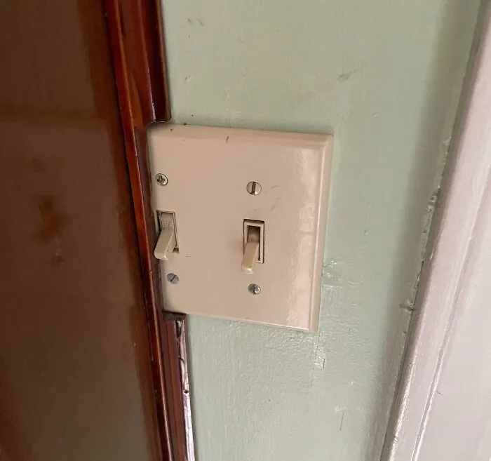 A light switch plate awkwardly cut into a door frame, illustrating DIY projects.